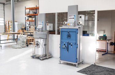 Blaue elektrische Ballenpresse an einer Wand mit Abfallpresse daneben